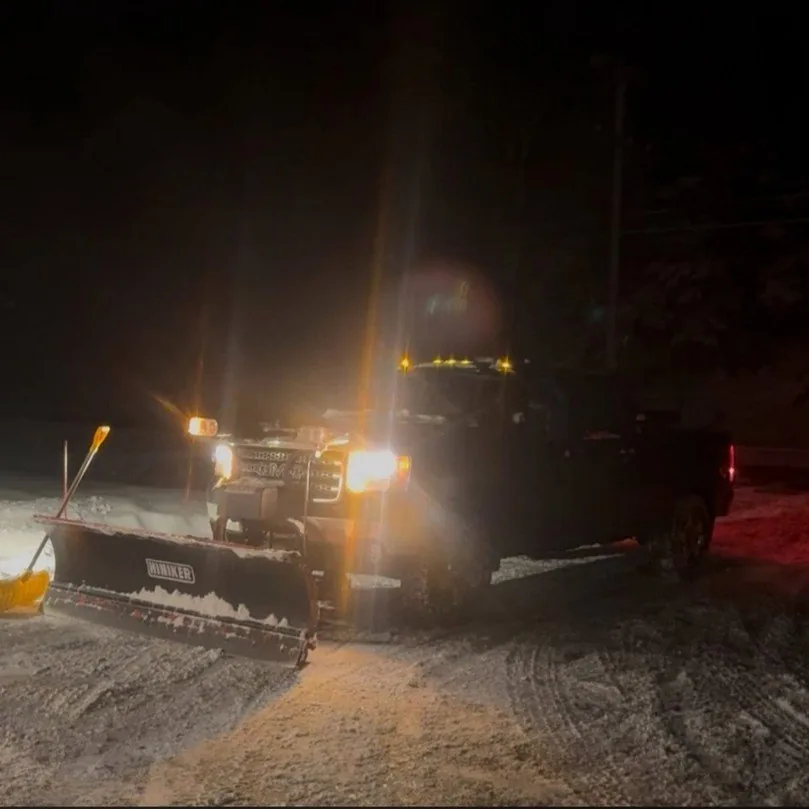 Truck with a plow on a snow-covered road at night